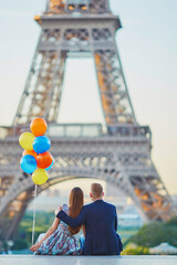 Wall Mural - Couple with colorful balloons looking at the Eiffel tower