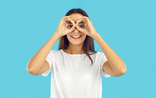 Happy Pretty Woman Looking Through Pretend Binoculars. Cheerful Beautiful Young Brunette Lady In White T Shirt Forming Circles With Her Hands, Doing Binoculars Gesture, Looking In Distance And Smiling