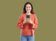 © Studio Romantic - Smiling brunette young woman taking photo on smartphone. Attractive positive girl in casual clothes taking picture with mobile phone. Optimistic woman using phone for photographing or communication