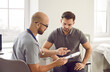 © Studio Romantic - Doctor talks to his patient after a medical examination at the clinic. Young male physician shows a clipboard with the results of some medical tests they did and explains what this all means