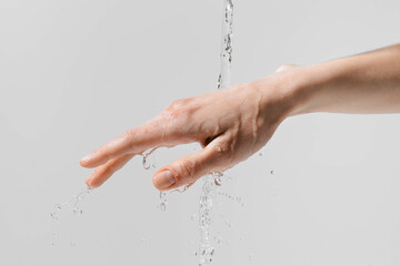 Female hand under a stream of water on a white isolated background. Concept of moisturizing cosmetics for hands, care products and rejuvenation. Image for your design