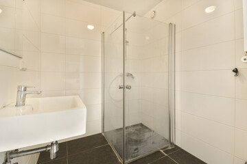 a modern bathroom with white tile walls and black tiles on the floor, there is a glass shower stall door