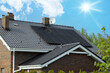 Modern house, dark solar panels, sunlit sky. Roof and photovoltaic technology.