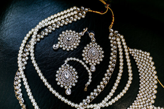 Indian bride's beautiful wedding jewelry decorated with pearls on black surface