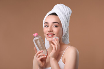 Wall Mural - Beautiful woman in terry towel removing makeup with cotton pad on beige background