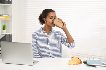 Canvas Print - African American intern drinking coffee at white table in office