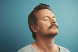 Fototapeta  - Portrait of a handsome man with closed eyes on a blue background