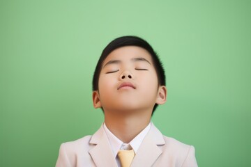 Portrait of cute asian boy in suit and tie on green background