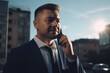 © Lee John - Businessman Smiling on Phone Call in the Busy City with Sun Rays With Generative AI Technology