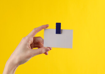 Canvas Print - Hand holds a badge on a clip, yellow background