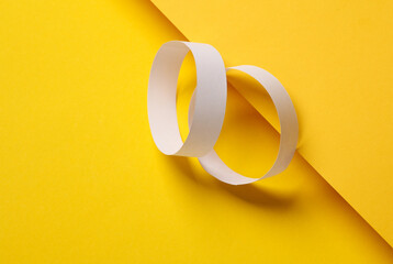 Wall Mural - Two white paper bracelets on a yellow background