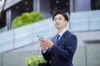 © west_photo - 20代日本人ビジネスマンがスマートフォンを使用して仕事をしている春のイメージ