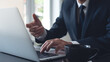 © tippapatt - Businessman online meeting via laptop computer at modern office, closeup. Business man working on laptop, searching the information, internet networking, corporate business