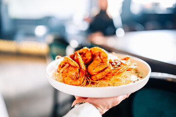 shrimps on a plate in the hands of waiter