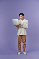 Wall Mural - Portrait of smiling young handsome businessman holding and using a laptop