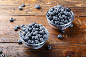 Wall Mural - Freshly picked blueberries in a glass bowl on a wooden background. Healthy food and nutrition concept.