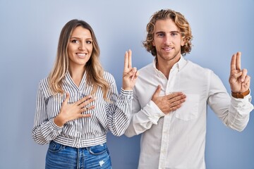 Sticker - Young couple standing over blue background smiling swearing with hand on chest and fingers up, making a loyalty promise oath