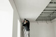 The worker attaches plasterboard on metal frame. Installation of ceiling