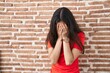 © Krakenimages.com - Young teenager girl standing over bricks wall with sad expression covering face with hands while crying. depression concept.