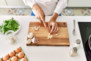 Poster - Young blonde woman cutting garlic at kitchen