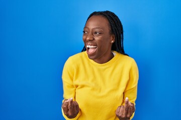 Wall Mural - Beautiful black woman standing over blue background showing middle finger doing fuck you bad expression, provocation and rude attitude. screaming excited