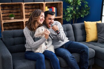 Poster - Man and woman singing song sitting on sofa with dog at home