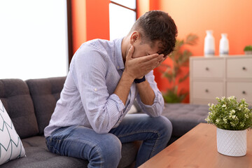 Poster - Young hispanic man stressed sitting on sofa at home