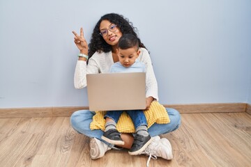 Sticker - Young hispanic mother and kid using computer laptop sitting on the floor smiling looking to the camera showing fingers doing victory sign. number two.