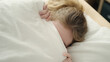 © Krakenimages.com - Young blonde woman lying on bed covering face with blanket at bedroom