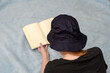 Kobieta czytająca książkę na kocu w kapeluszu przeciwsłonecznym