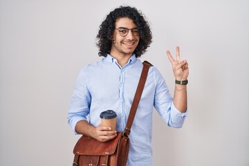 Sticker - Hispanic man with curly hair drinking a cup of take away coffee smiling with happy face winking at the camera doing victory sign with fingers. number two.