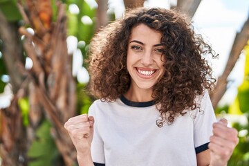 Sticker - Hispanic woman with curly hair standing outdoors screaming proud, celebrating victory and success very excited with raised arms