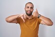 © Krakenimages.com - Hispanic man with beard standing over white background doing thumbs up and down, disagreement and agreement expression. crazy conflict