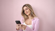 © Krakenimages.com - Young blonde woman smiling confident using smartphone over isolated pink background