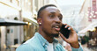 © serg - Attractive carefree friendly joyful young black-skinned guy with stylish beard enjoying phone conversation during his walk on the street with cozy street cafes in summertime