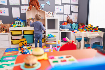 Adorable caucasian boy playing on back view at kindergarten