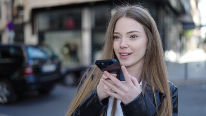 Sticker - Young blonde woman sending voice message with smartphone at street