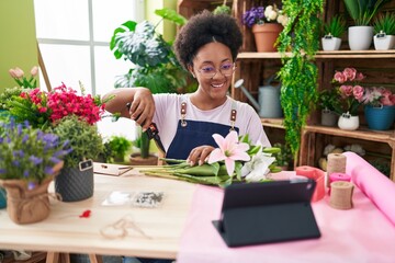 Poster - African american woman florist make bouquet of flowers watching video on touchpad at flower shop