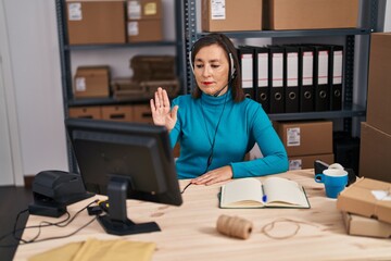 Wall Mural - Middle age hispanic woman working at small business ecommerce on customer support with open hand doing stop sign with serious and confident expression, defense gesture