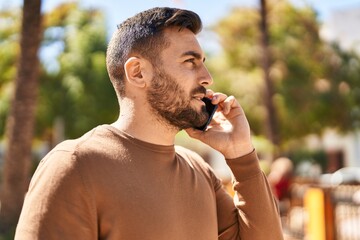 Sticker - Young hispanic man talking on the smartphone at park