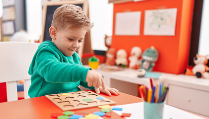 Wall Mural - Adorable caucasian boy playing with maths puzzle game sitting on table at kindergarten