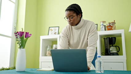 Poster - African american woman using laptop standing at dinning room