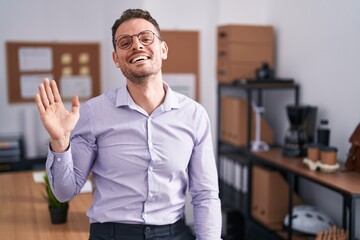 Sticker - Young hispanic man at the office waiving saying hello happy and smiling, friendly welcome gesture