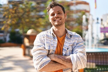 Wall Mural - Young hispanic man smiling confident standing with arms crossed gesture at park