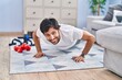 Young hispanic man smiling confident training push up at home