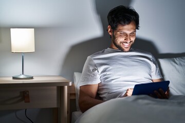 Sticker - Young hispanic man using touchpad sitting on bed at bedroom