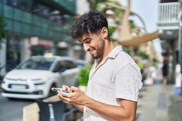 Canvas Print - Young arab man smiling confident watching video on smartphone at street