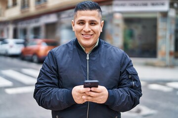 Sticker - Young latin man smiling confident using smartphone at street