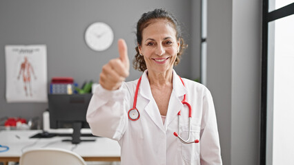 Canvas Print - Middle age hispanic woman doctor doing thumb up at clinic