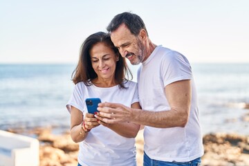 Sticker - Middle age man and woman couple using smartphone standing together at seaside